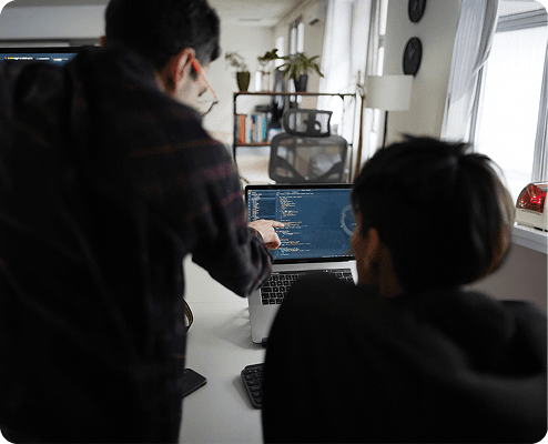 Developers collaborating at workstations with code on screen, representing professional engineering standards.