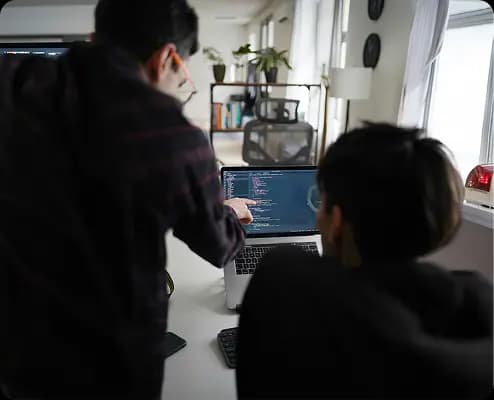 Developers collaborating at workstations with code on screen, representing professional engineering standards.